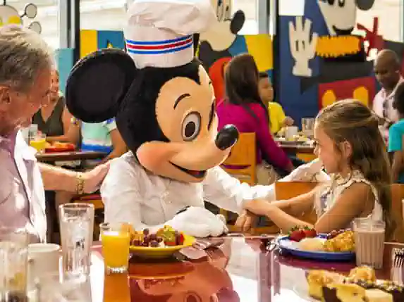 Chef Mickey comiendo con pequeña en Orlando Disney